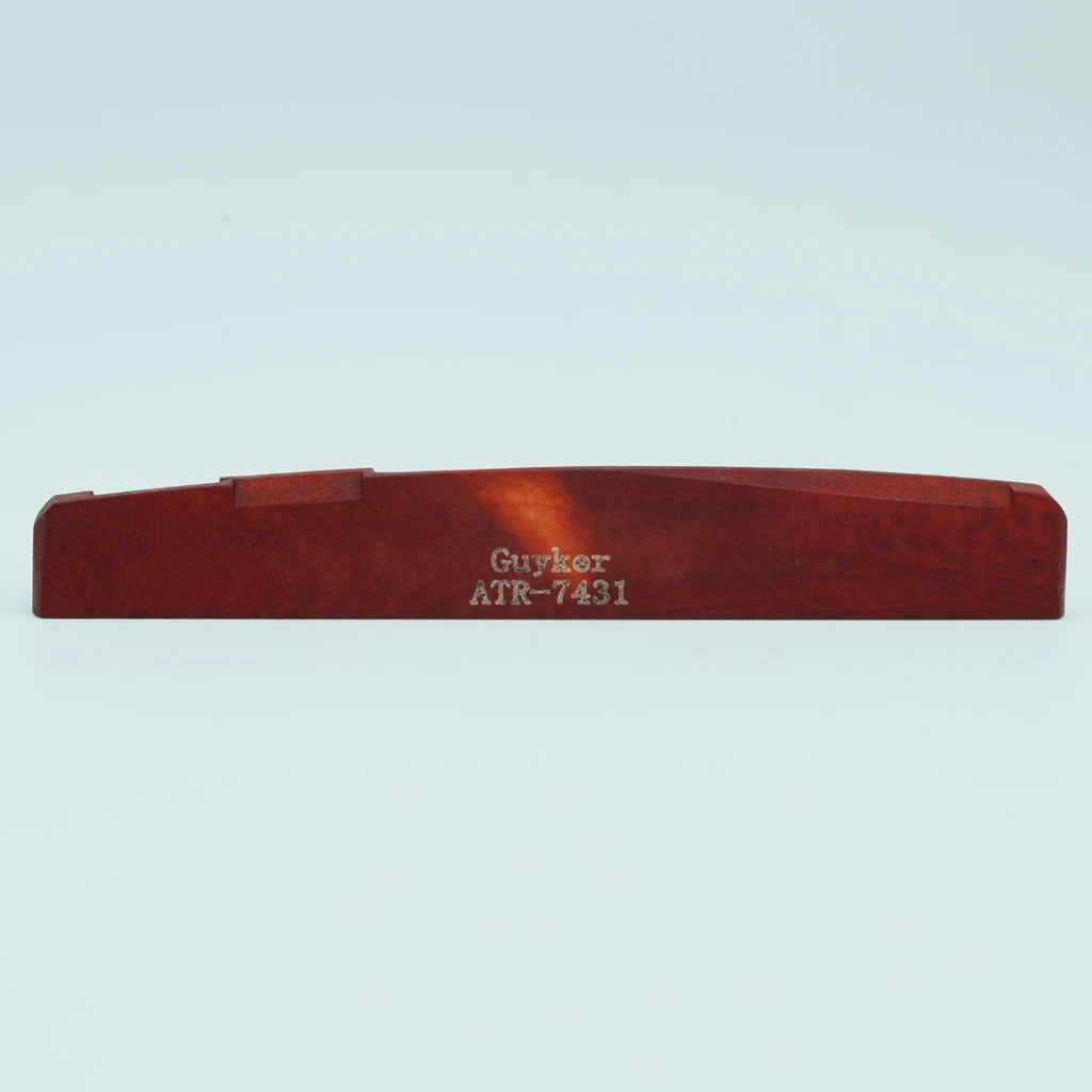 A wooden acoustic guitar bridge saddle with the name Guyker and model ATR-7431 engraved on it.