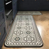 A long rectangular kitchen rug with a classic black and white Persian-style pattern is displayed on a wooden floor.