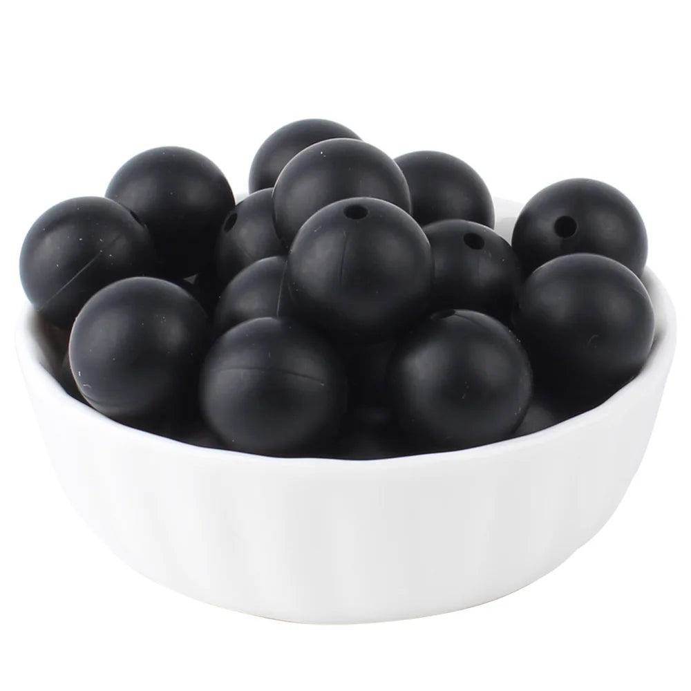 A white bowl filled with small black silicone beads for jewelry making