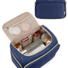 A navy blue quilted travel toiletry bag with a gold zipper and handle, open to show various cosmetic products.