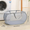 A gray folding mesh laundry basket with handles is shown next to a washing machine.