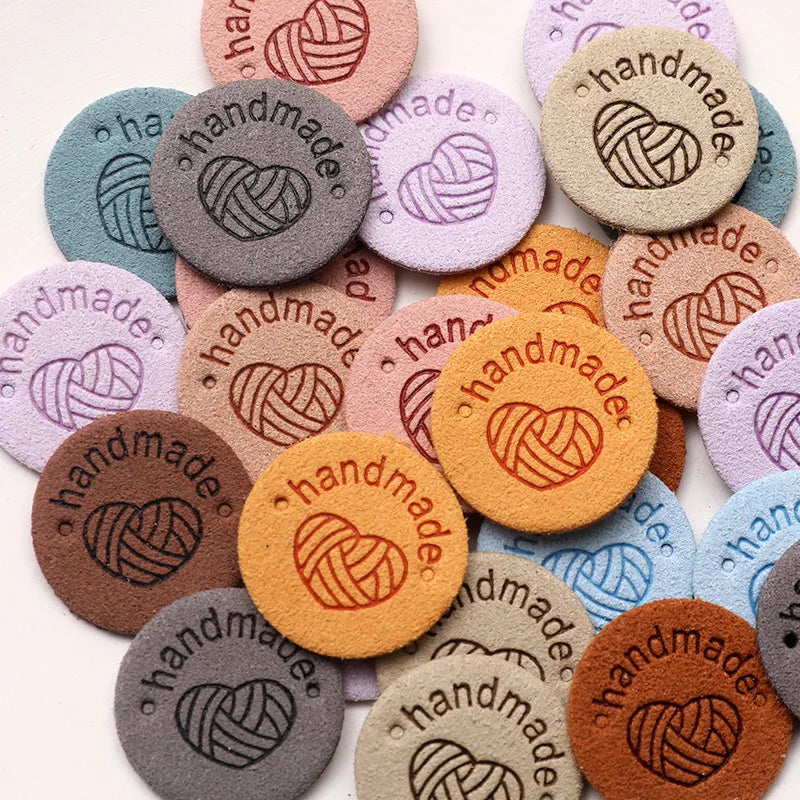 A collection of round, handmade PU leather labels in various pastel and earthy tones.