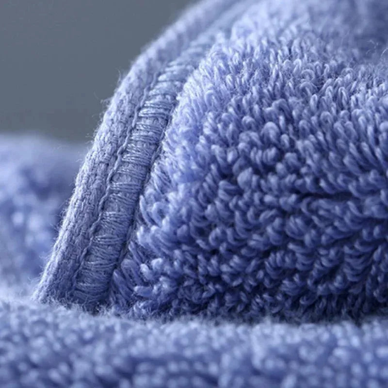 Close-up of a soft blue bath towel showing the textured fabric and stitching detail.