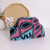 A hand-knit clutch bag featuring pink, teal, and black geometric patterns.