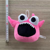 Pink plush toy of Opila Bird with large eyes and a wide mouth, measured against a ruler.