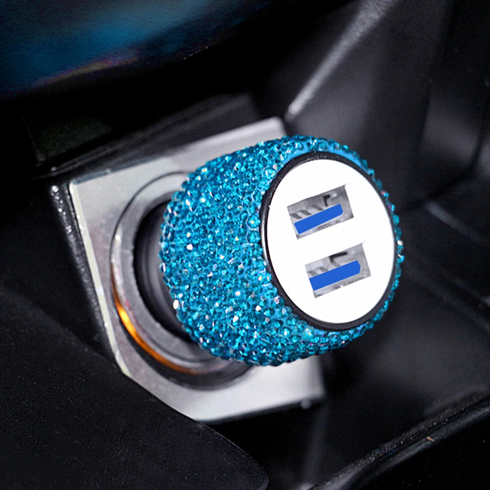 A close-up of a blue rhinestone dual USB car charger with white accents inside a black device slot.