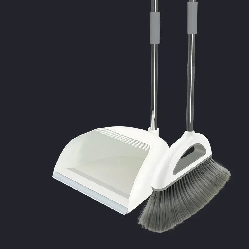 A white broom and dustpan set with a floor wiper tool against a dark background.