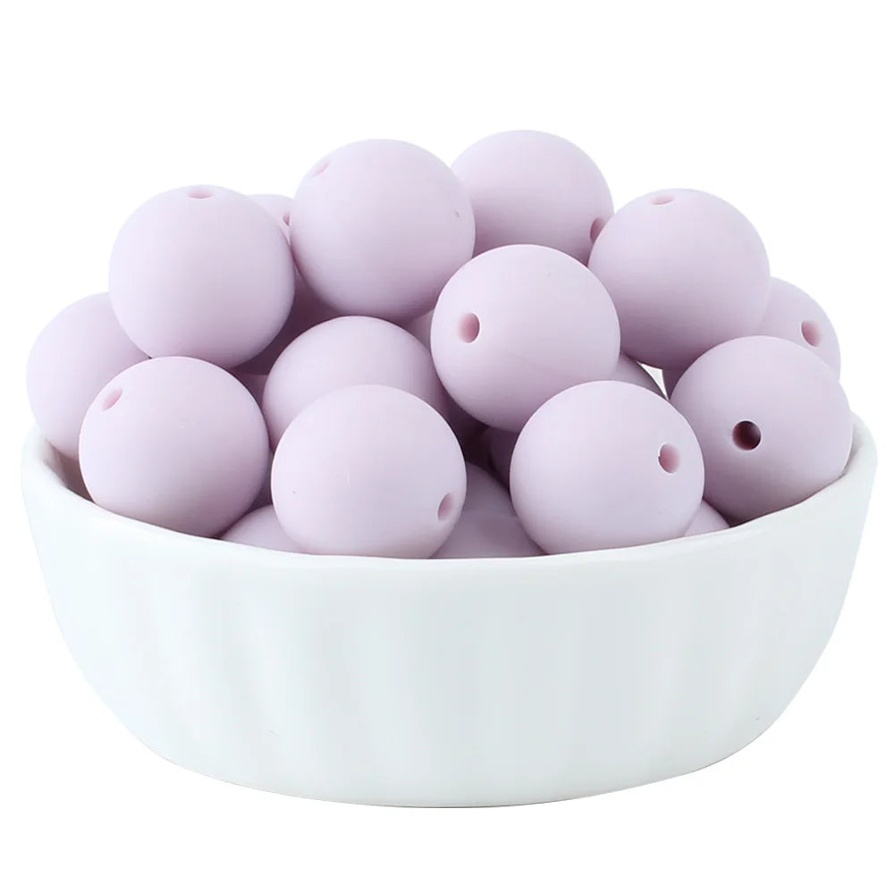 A white bowl filled with numerous light pink silicone beads for jewelry making