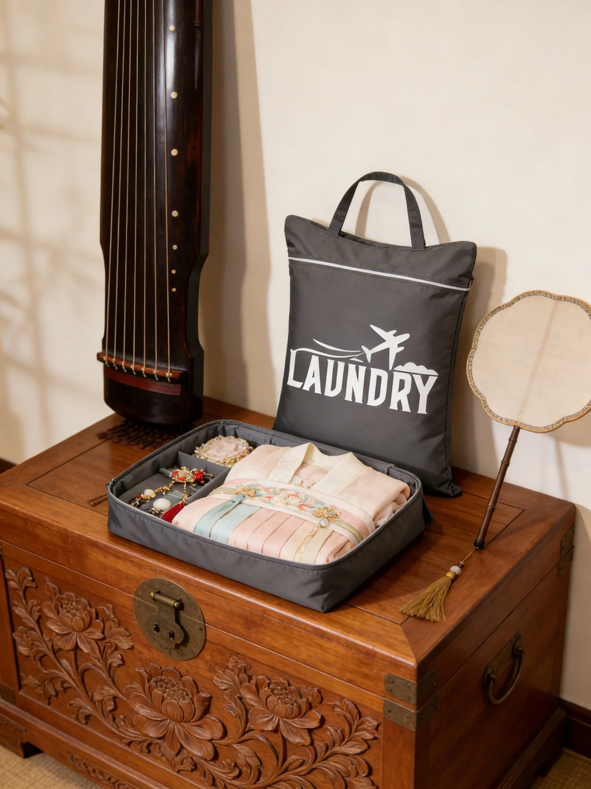 A dark gray laundry bag rests on a wooden trunk next to a tall wooden object.