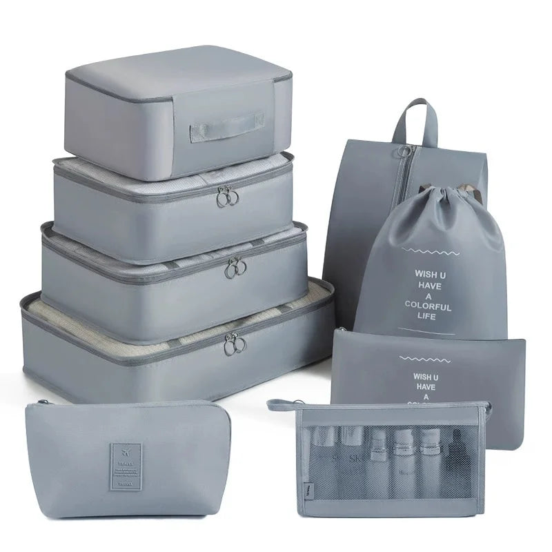 A set of gray travel packing cubes and storage organizer bags stacked and laid out.