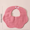 A pink soft cotton baby bib with a ruffle trim is shown against a light background.