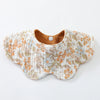 A light floral patterned cotton baby feeding bib with a wooden closure.