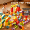 A child is playing with a colorful electric track train set made of interlocking blocks on a wooden floor.
