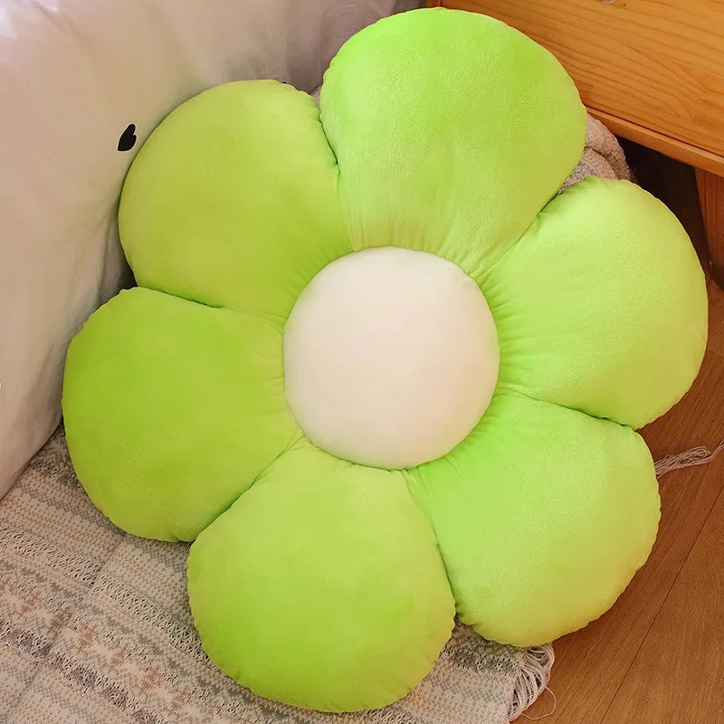 A bright lime green sunflower plush pillow with a white center, resting on a beige textured surface.