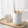 A white bamboo bathroom organizer set featuring a soap dispenser and a toothbrush holder on a wooden tray.
