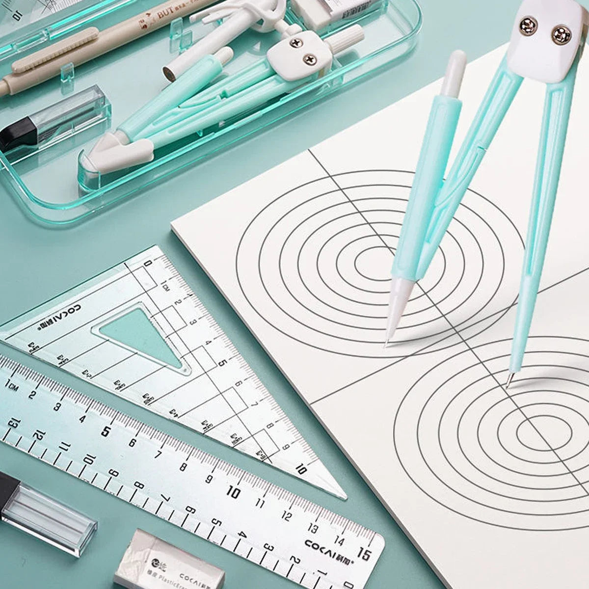 A complete geometry drawing set featuring a compass, protractor, and rulers laid out on a white sheet of paper.