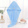 Light blue microfiber towel wrap for hair displayed on a glass stand.