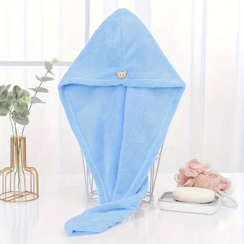 Light blue microfiber towel wrap for hair displayed on a glass stand.