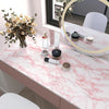 A display of cosmetic products and dried flowers on a pink marble countertop.