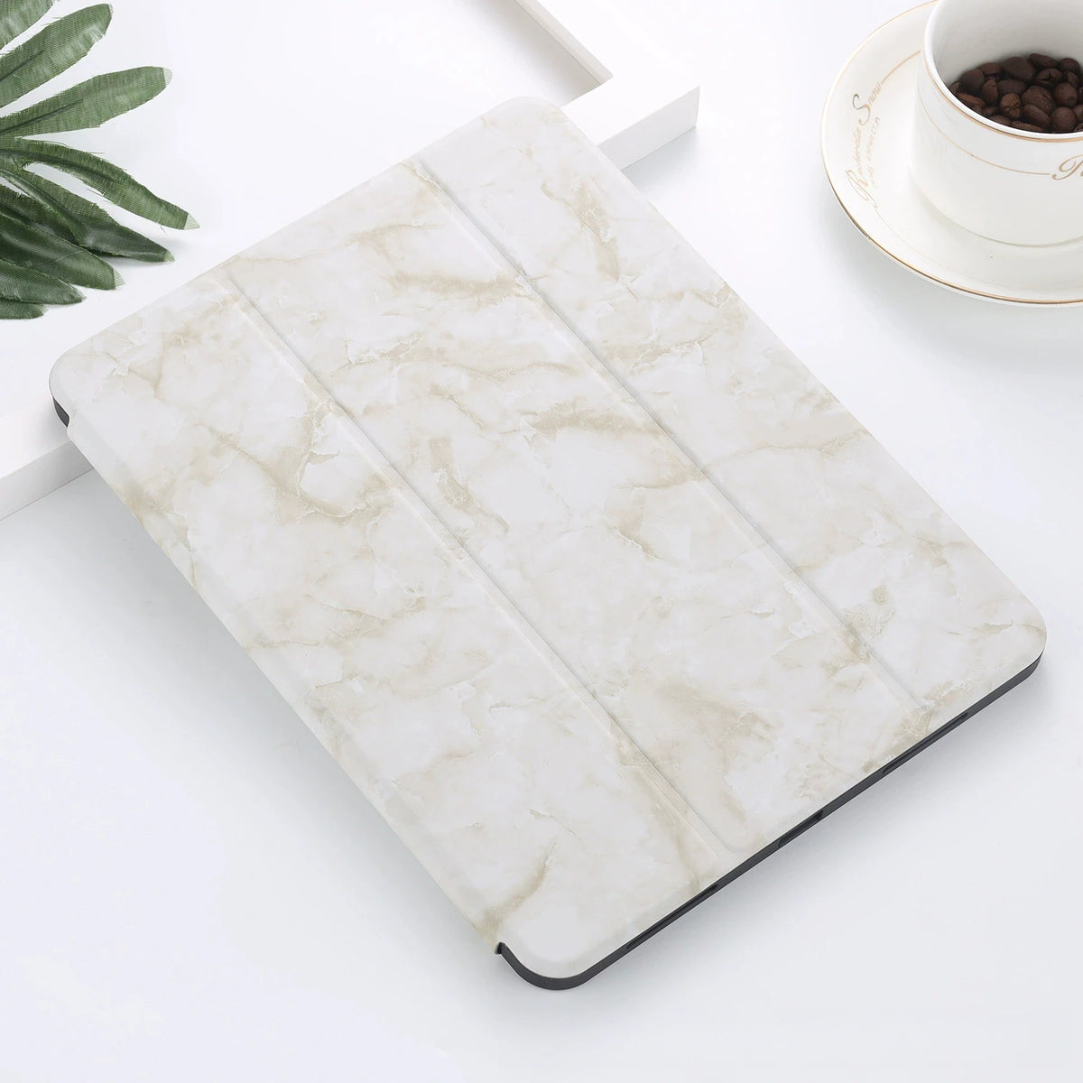 A white marble patterned iPad Pro case with a built-in pencil holder resting on a white surface.