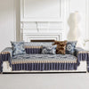 A navy blue patterned sofa cover with quilted protection displayed in a bright room.