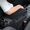 A hand rests on a black plush car armrest cushion in a vehicle interior.