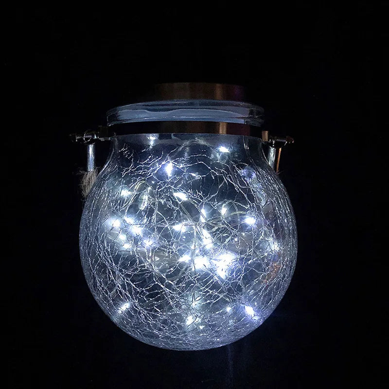 A spherical crackle glass solar lantern emitting a warm ambient glow against a dark background.