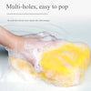 A hand is squeezing a yellow multi-hole sponge, covered in white soap suds.