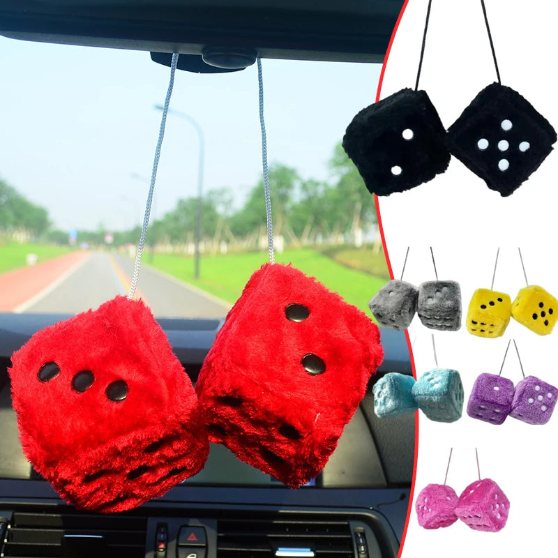 Two red plush velvet dice pendants hanging from a car mirror.