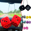 Two red plush velvet dice pendants hanging from a car mirror.