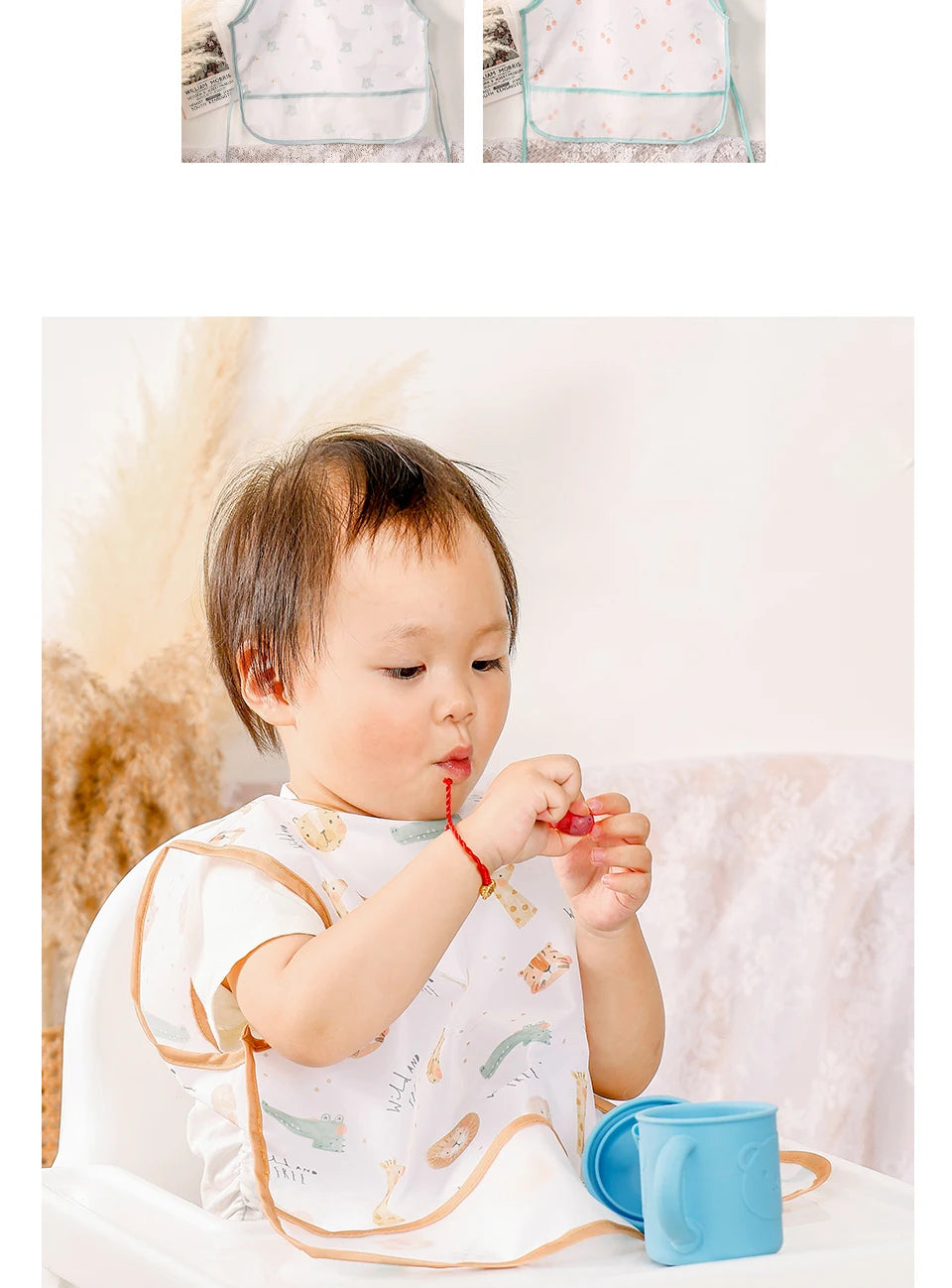 A baby is shown wearing a white and gold patterned waterproof full-body feeding bib with a sleeveless design.