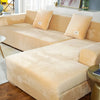 A beige plush velvet elastic sofa cover is shown on an L-shaped sofa, featuring decorative pillows.