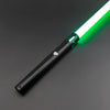 A black lightsaber with a green blade and metal hilt is shown diagonally against a dark gray background.