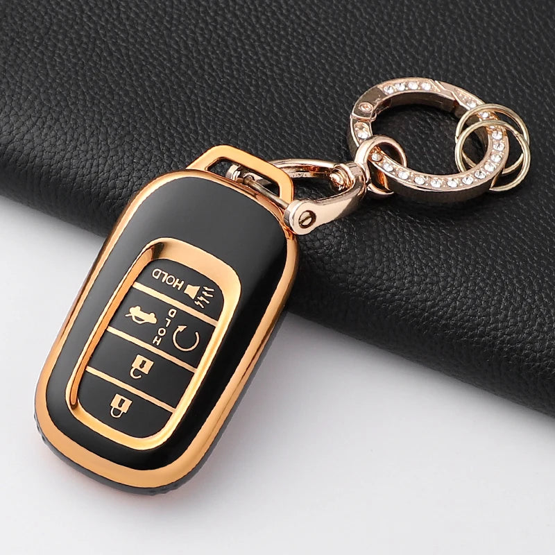 A gold-toned key fob with a black anti-scratch TPU protective case is shown attached to a silver chain.