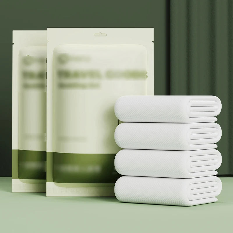 Une pile de draps jetables pour lit double blancs et leur emballage sont exposés sur une surface verte.