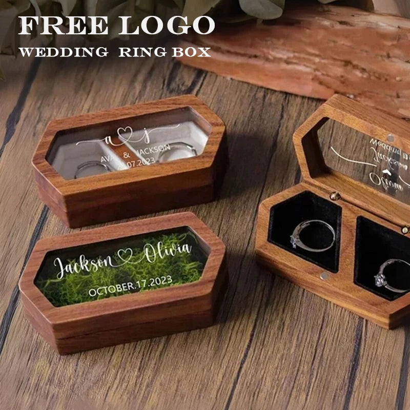 Three wooden ring boxes engraved with names and dates resting on a wooden surface.