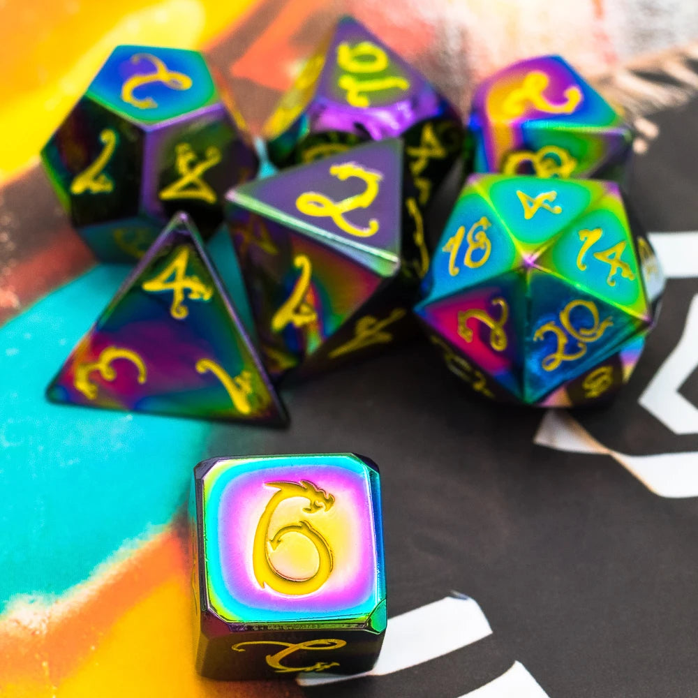 A collection of seven metal polyhedral dice with a dragon font design scattered on a dark surface.