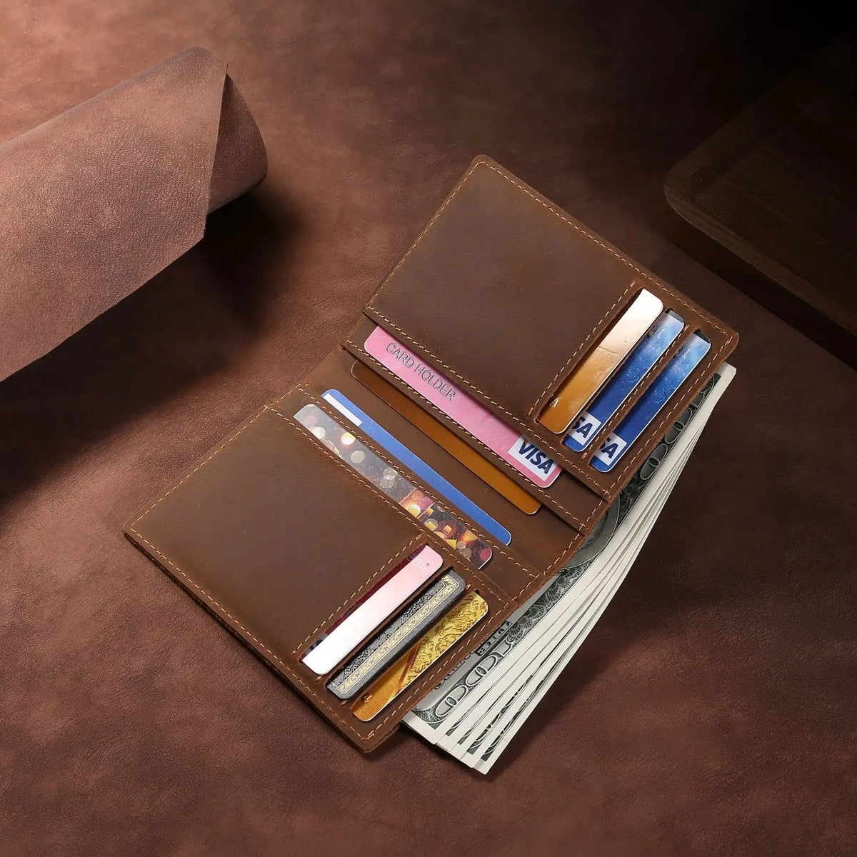 A brown leather bifold wallet holds several cards and a stack of cash on a dark surface.