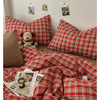 A close-up of a red and green plaid duvet cover set with matching pillows and bedding on a bed.