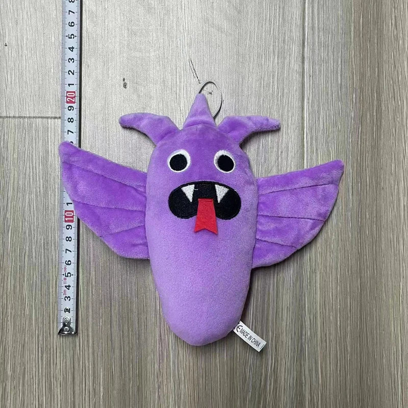 A purple plush toy shaped like a bird with large wings and an open mouth, measured against a ruler.