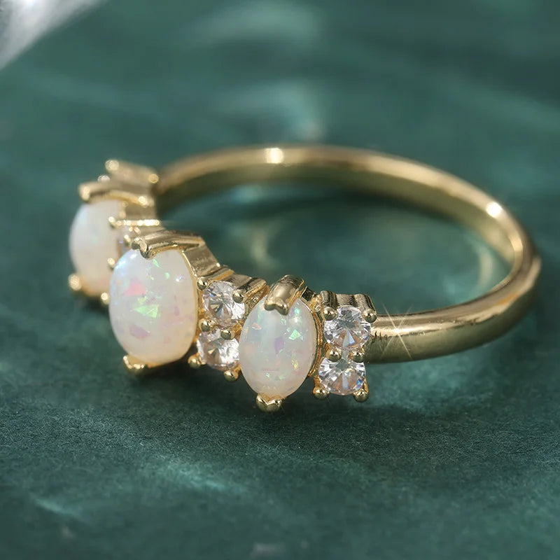 Bague plaquée or featuring une opale synthétique ovale et des diamants clairs, sertie dans une bande délicate.