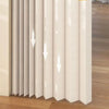 A vertical beige door curtain with vertical pleats and a translucent fabric, shown in a modern interior setting.