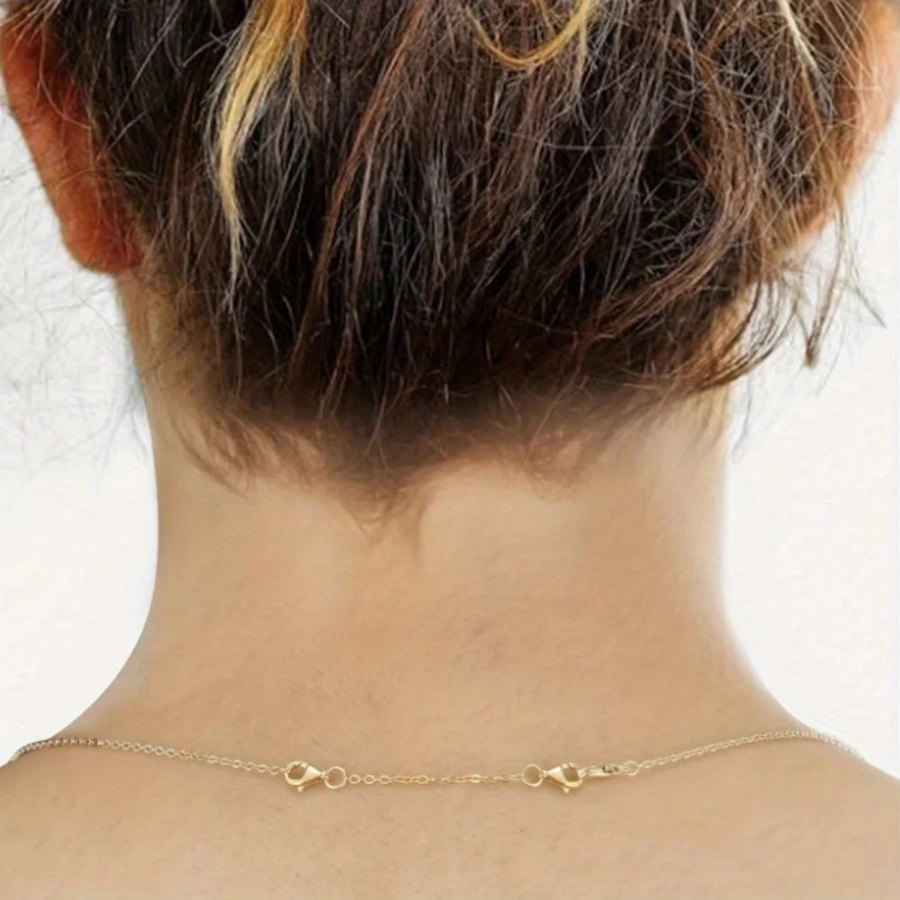 A close-up of a gold-plated necklace extender chain with lobster clasps against a person's neck.