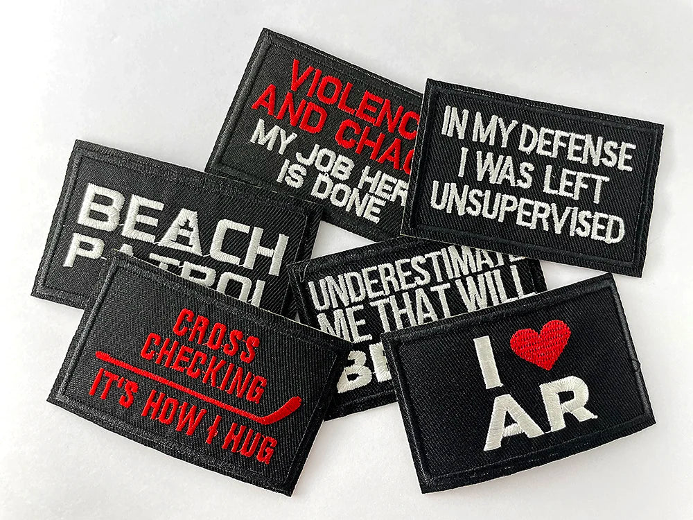 A collection of black embroidered iron-on patches with text such as VIOLENCE AND CHAOS and I AM AR