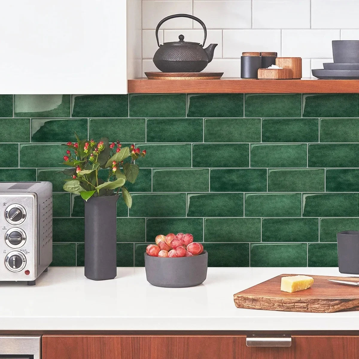 A kitchen backsplash featuring dark green subway tiles, a white countertop, and various cooking and food items.