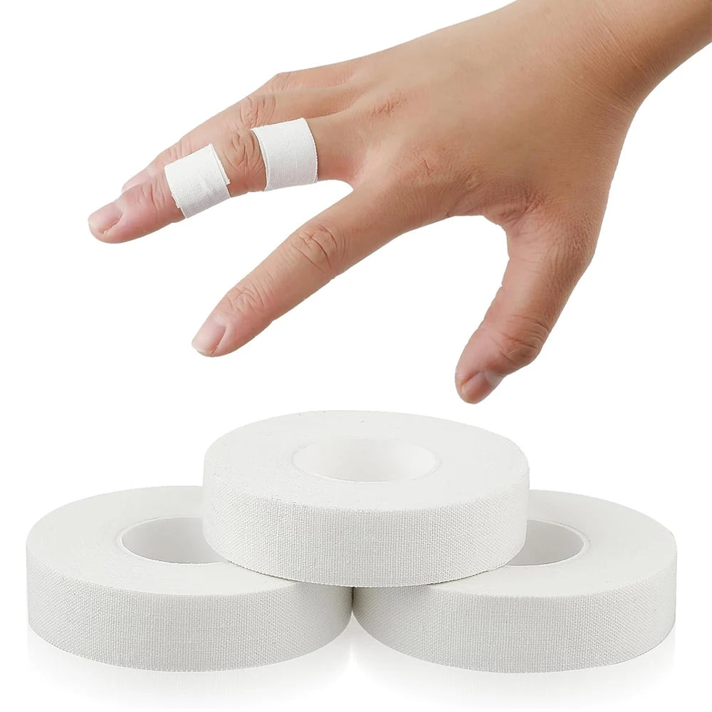 A hand is applying white athletic finger tape to a finger, with several rolls of the same tape visible below.