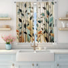 A set of two sheer curtains with an abstract leaf print in muted greens and browns hanging in a window.