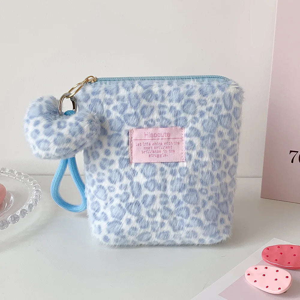 A light blue and white leopard print cosmetic bag with a gold clasp and light blue strap.