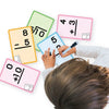 A person is writing on several colorful math practice cards, including ones showing equations and numbers.
