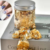 Jar of metallic gold foil flakes for crafting and nail art displayed on a box.